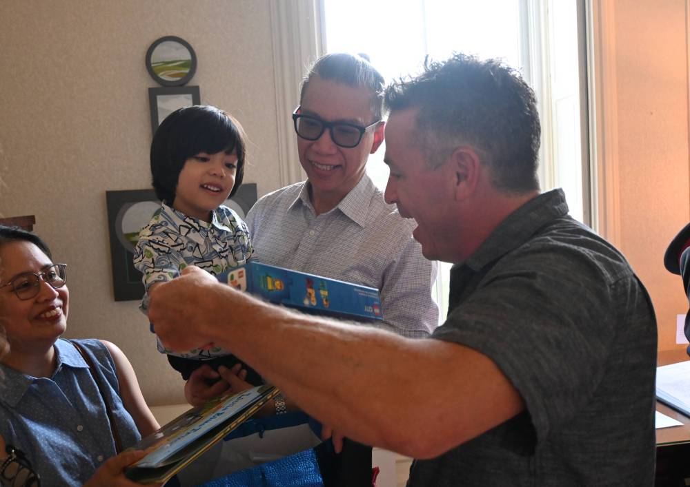 From left, Ana Bautista, John Joseph Bautista and their son Andres receive a gift from Christian Clavelle, who saved Andres from drowning. (Matthew Frank / Free Press)
