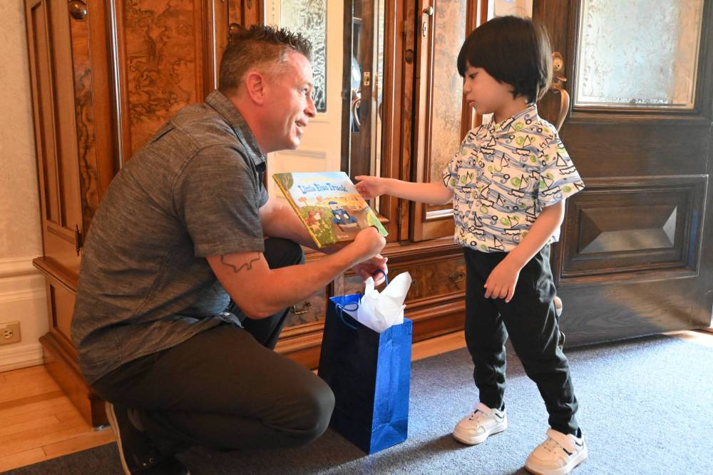 Christian Clavelle (left) hands a gift to Andres Bautista, who Clavelle saved from drowning at St. Malo Provincial Park on August 3, 2024. (Matthew Frank / Free Press)