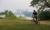 MIKE DEAL / FREE PRESS
                                Wildfire smoke shrouds downtown high-rises as a cyclist makes their way along a bike path beside the Red River Friday morning.