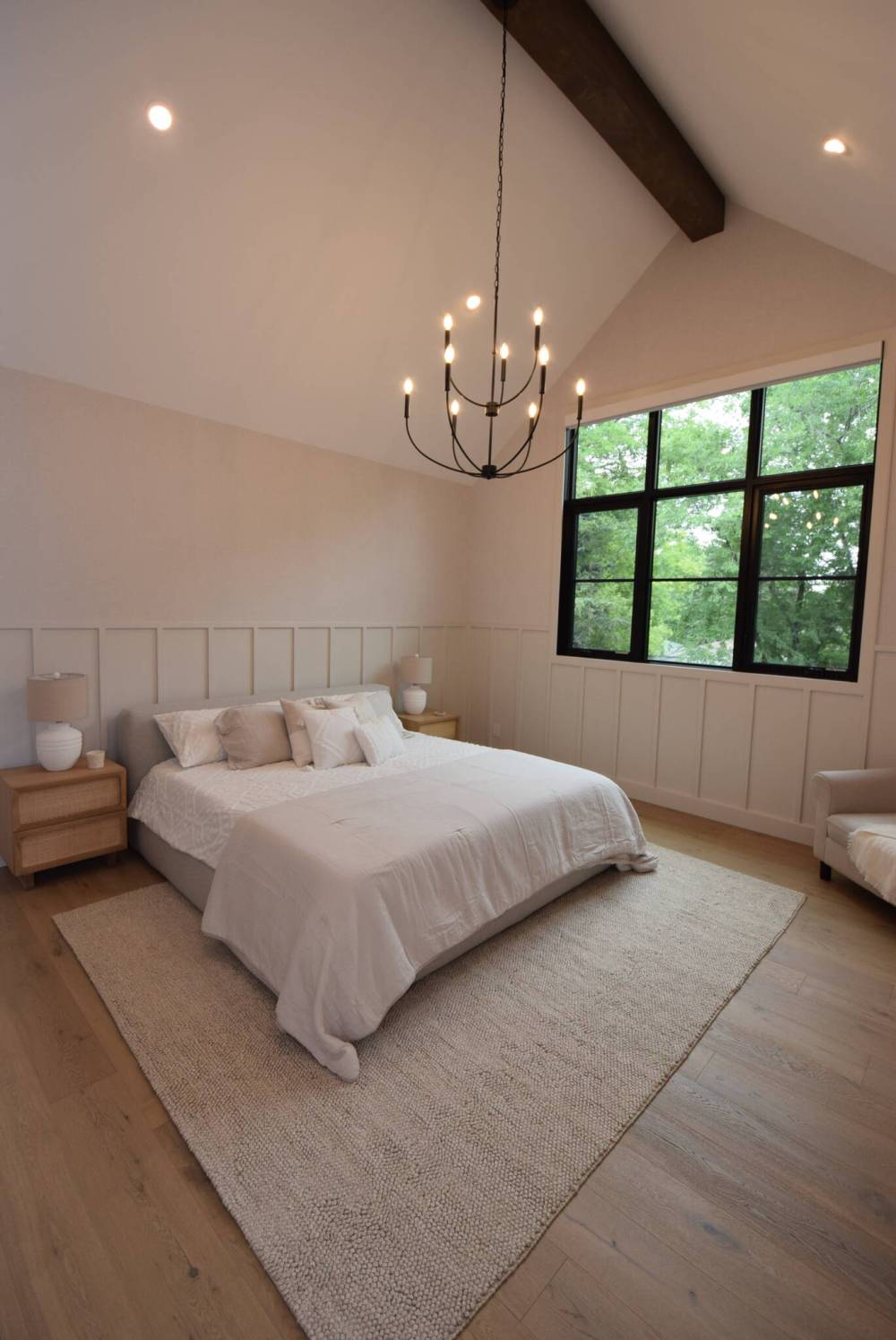 The private primary suite has a vaulted, beamed ceiling and a huge window that lets in tons of natural light and frames tree views from up high.