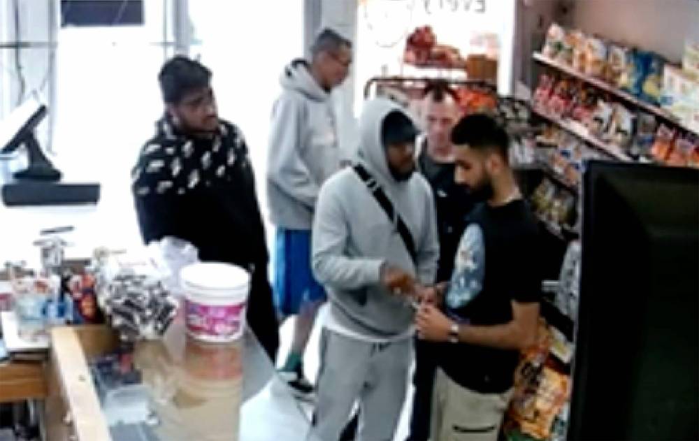 SUPPLIED
Security video shows a group of four men suspected of extortion interacting with a store employee, right, at Magnus Foods Wednesday.