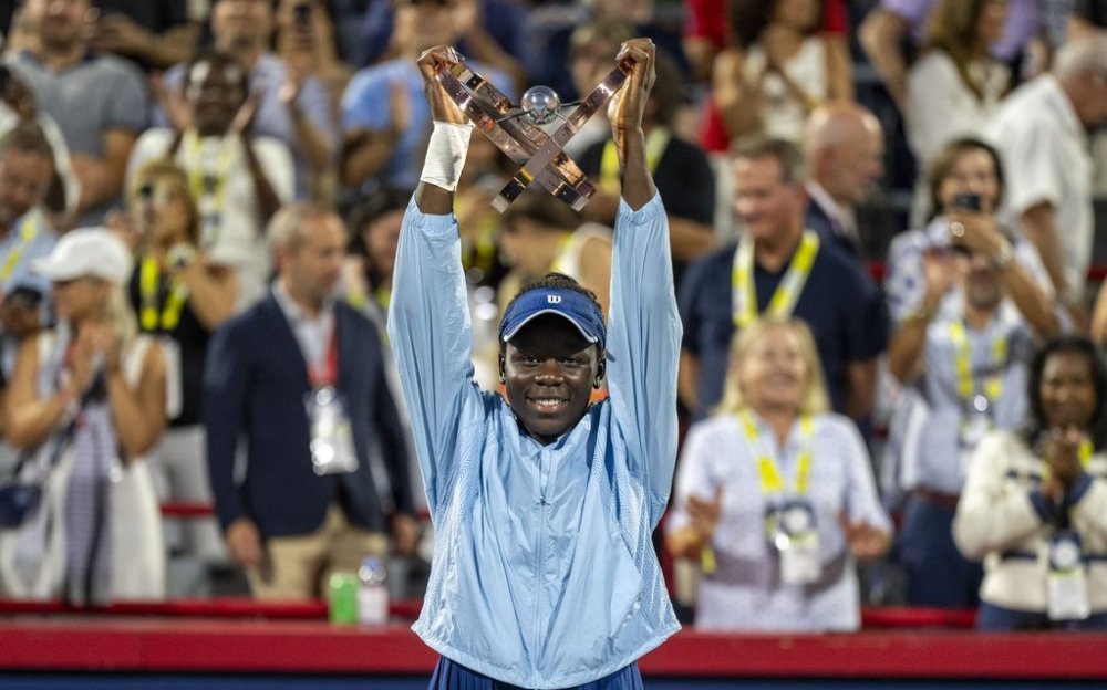 Victoria Mboko of Canada hoists the trophy following her win over Naomi Osaka of Japan during finals tennis action at the National Bank Open in Montreal, Thursday, Aug. 7, 2025. THE CANADIAN PRESS/Christinne Muschi