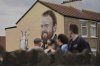 People stop and look at a mural of golfer Shane Lowry of Ireland, holding the Claret Jug trophy, in Portrush, ahead of the 2025 British Open golf championship at the Royal Portrush Golf Club, Northern Ireland, Monday, July 14, 2025. (AP Photo/Francisco Seco)