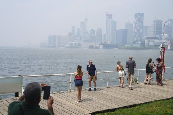 Tourists pose for a photo against a city view of Toronto obscured by wildfire smoke on Monday. (Chris Young / The Canadian Press)