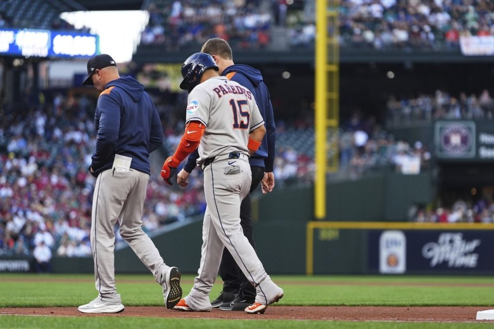 Houston Astros' Isaac Paredes (15) is walked back to the dugout with an apparent injury after running to first base on a single against the Seattle Mariners during the third inning of a baseball game Saturday, July 19, 2025, in Seattle. (AP Photo/Lindsey Wasson)