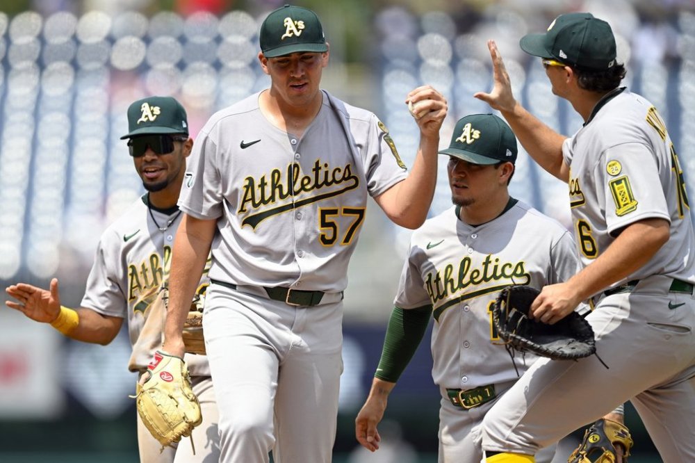 Athletics starting pitcher Jacob Lopez, waiting to be relieved, is congratulated by teammates on the mound after pitching seven and two thirds innings of shutout baseball against the Washington Nationals, Thursday, Aug. 7, 2025, in Washington. (AP Photo/John McDonnell)