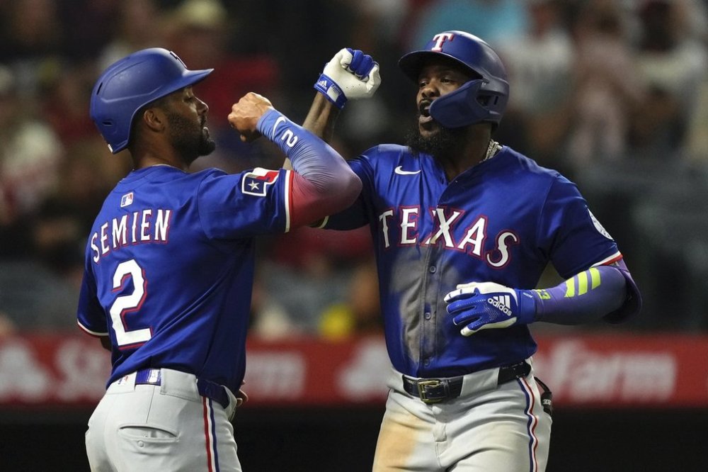 Texas Rangers' Adolis Garcia, right, is congratulated by Marcus Semien after hitting a two-run home run during the eighth inning of a baseball game against the Los Angeles Angels, Thursday, July 10, 2025 in Anaheim, Calif. (AP Photo/Mark J. Terrill)