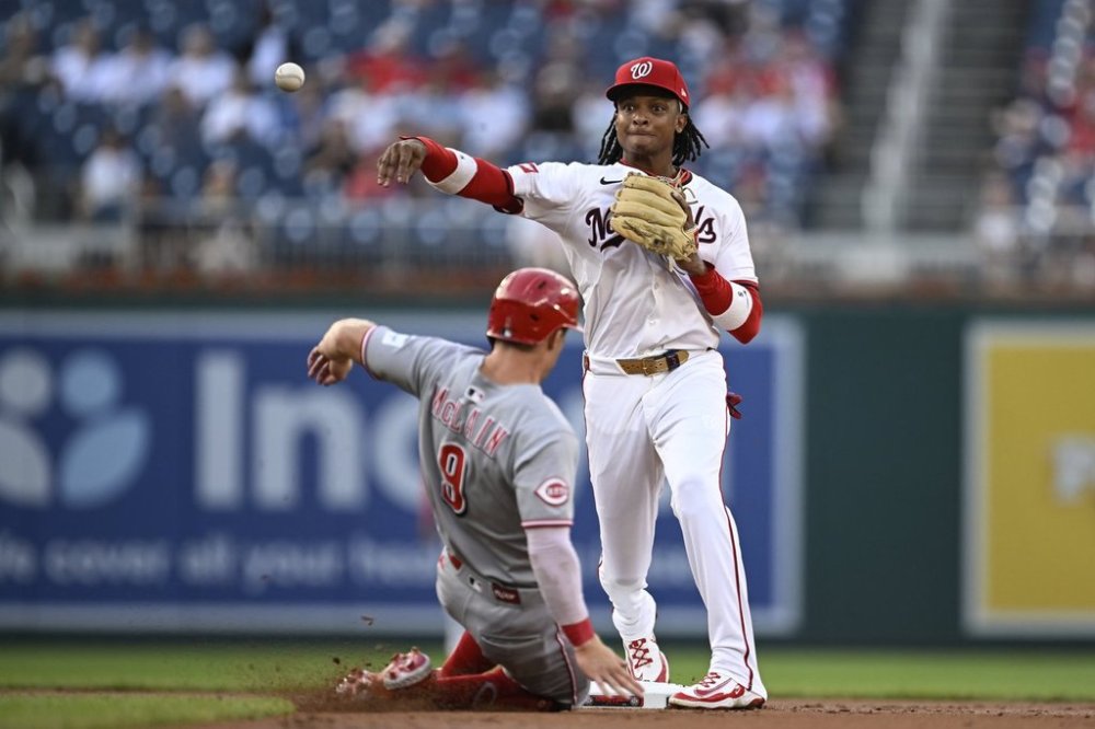 Washington Nationals shortstop CJ Abrams gets the force out at second base of Cincinnati Reds' Matt McLain and turns the double play on a ball hit by Elly De La Cruz against pitcher Brad Lord during the first inning of a baseball game in Washington, Tuesday, July 22, 2025. (AP Photo/Terrance Williams)