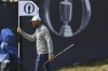 Scottie Scheffler of the United States hols the pin flag as he walks on the 17th green during a practice round for the 2025 British Open golf championship at the Royal Portrush Golf Club, Northern Ireland, Monday, July 14, 2025. (AP Photo/Peter Morrison)