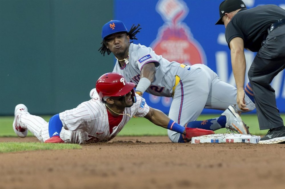 Philadelphia Phillies' Johan Rojas, left, is safe at second before New York Mets second baseman Luisangel Acuna can make the tag in the fourth inning of a baseball game, Sunday, June 22, 2025, in Philadelphia. (AP Photo/Laurence Kesterson)