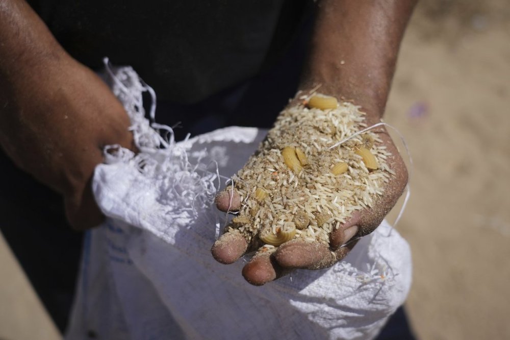 A Palestinian man displays the contents of humanitarian aid packages after they were airdropped into Zawaida, in the central Gaza Strip, Wednesday, July 30, 2025. (AP Photo/Abdel Karim Hanna)