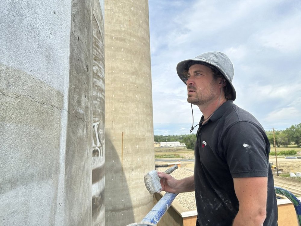 Artist Guido van Helten looks at the side of the silo where he is painting a mural on Monday, July 14, 2025, in Minot, N.D. (AP Photo/Jack Dura)