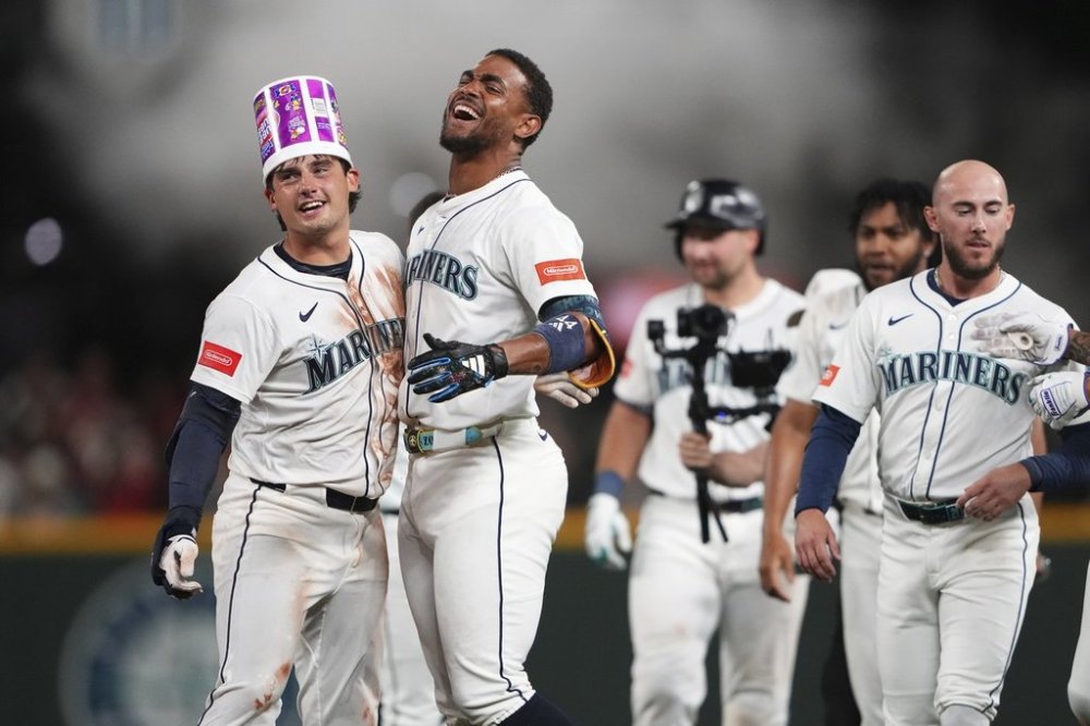 Seattle Mariners' Cole Young, left, celebrates with Julio Rodriguez, second from left, after hitting a game-winning single against the Houston Astros in the 11th inning of a baseball game Saturday, July 19, 2025, in Seattle. (AP Photo/Lindsey Wasson)