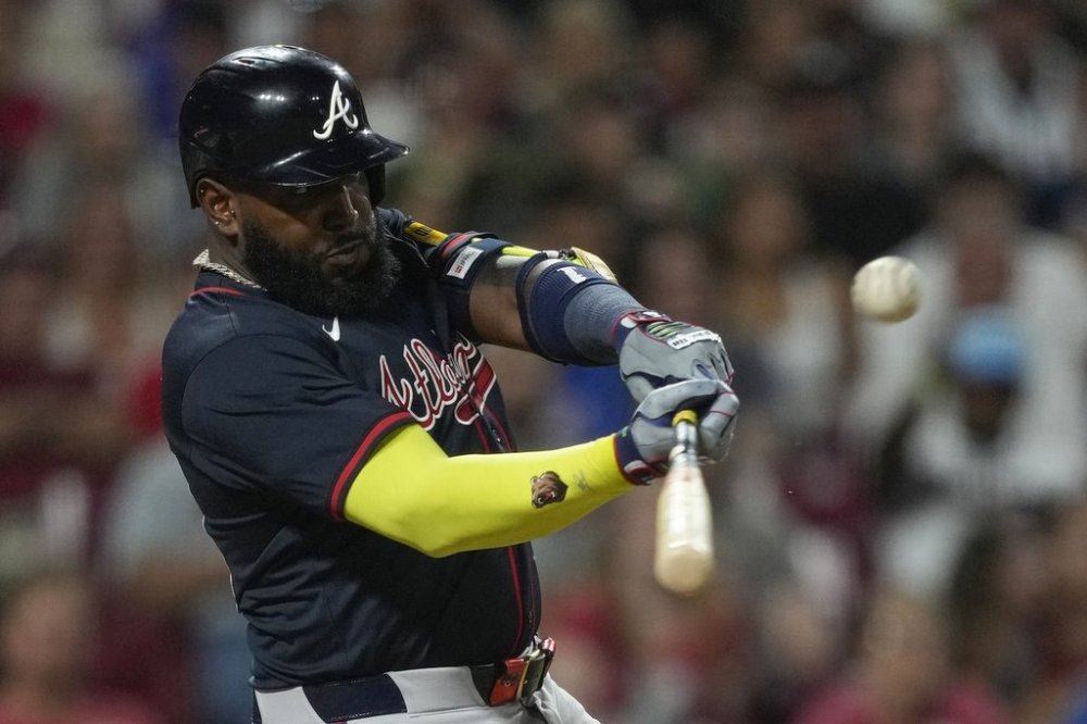 Atlanta Braves designated hitter Marcell Ozuna hits a sacrifice fly to score Matt Olson during the tenth inning of a baseball game against the Cincinnati Reds, Thursday, July 31, 2025, in Cincinnati. (AP Photo/Carolyn Kaster)