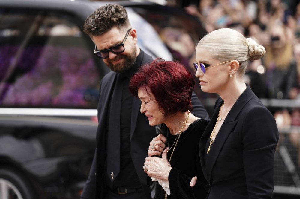 The family of Ozzy Osbourne from left, Jack Osbourne, Sharon Osbourne and Kelly Osbourne lay flowers and view the flowers left at the Black Sabbath Bridge bench on Broad Street in memory of Black Sabbath frontman Ozzy Osbourne ahead of the funeral procession, in Birmingham, England, Wednesday July 30, 2025. (Jacob King/PA via AP)