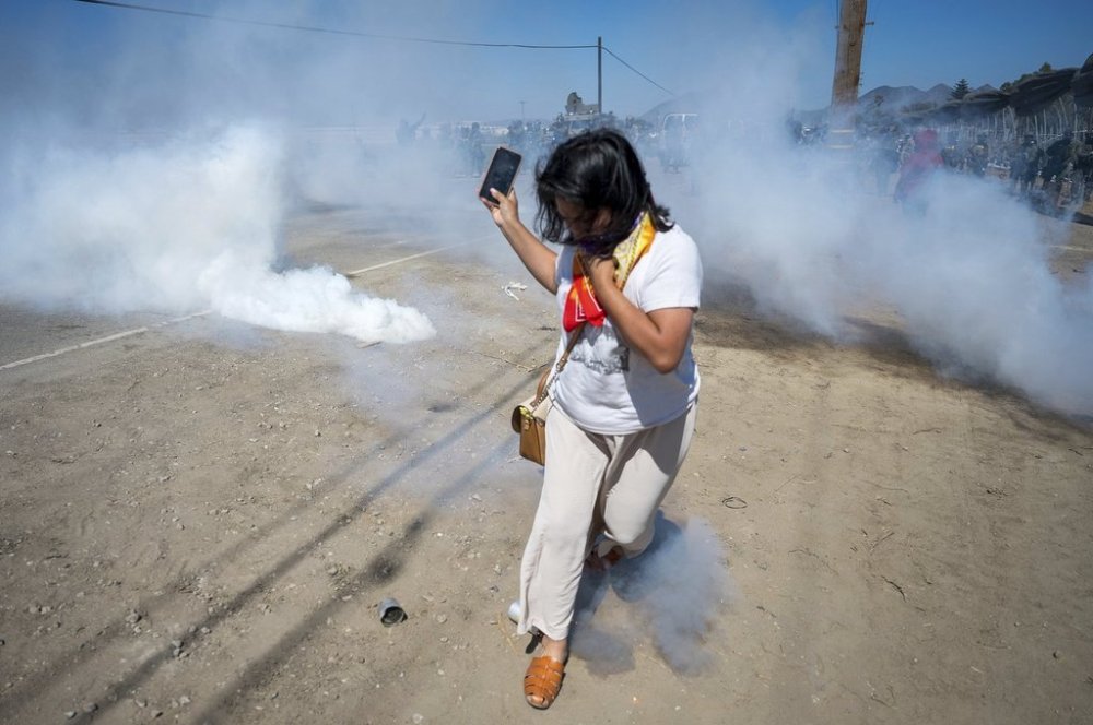 A protester runs from tear gas tossed by federal immigration agents to clear a path for the vehicles during a raid in the agriculture area of Camarillo, Calif., Thursday, July 10, 2025. (AP Photo/Michael Owen Baker)