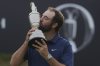 Scottie Scheffler of the United States kisses the Claret Jug trophy as he poses for photographers after winning the British Open golf championship at the Royal Portrush Golf Club, Northern Ireland, Sunday, July 20, 2025. (AP Photo/Jon Super)