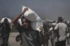 Palestinians carry sacks of flour unloaded from a humanitarian aid convoy that reached Gaza City from the northern Gaza Strip, Sunday, July 27, 2025. (AP Photo/Jehad Alshrafi)
