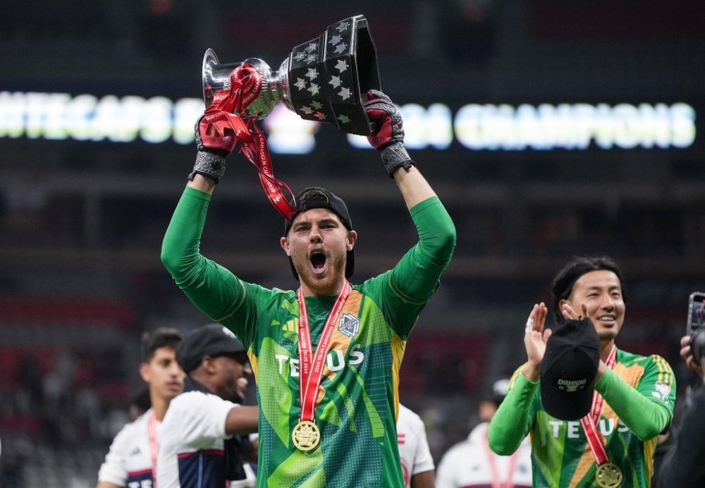 Vancouver Whitecaps goalkeeper Isaac Boehmer, front left, hoists the Voyageurs Cup as goalkeeper Yohei Takaoka, back right, applauds after Vancouver defeated Toronto FC on penalty kicks during the Canadian Championship final soccer match, in Vancouver, on Wednesday, September 25, 2024. THE CANADIAN PRESS/Darryl Dyck