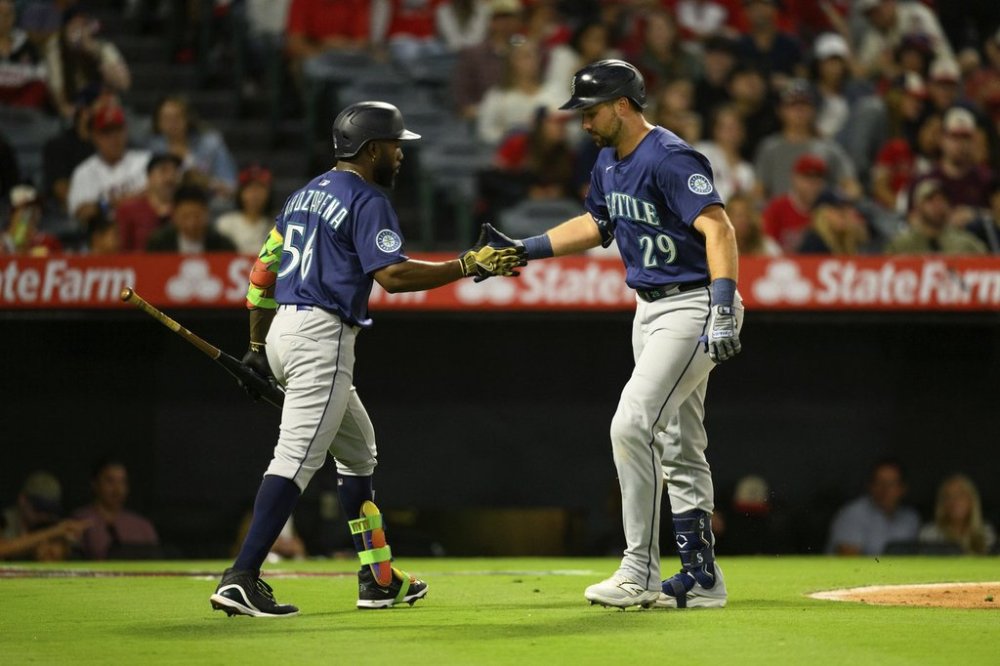 Seattle Mariners' Cal Raleigh, right, is greeted by Randy Arozarena, left, after hitting a home run during the sixth inning of a baseball game against the Los Angeles Angels, Saturday, July 26, 2025, in Anaheim, Calif. (AP Photo/William Liang)