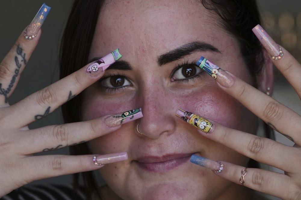 Mariam Camila Sosa strikes a pose to show off her freshly decorated fingernails, at a home-run nail salon in Havana, Cuba, Tuesday, June 24, 2025. (AP Photo/Ramon Espinosa)