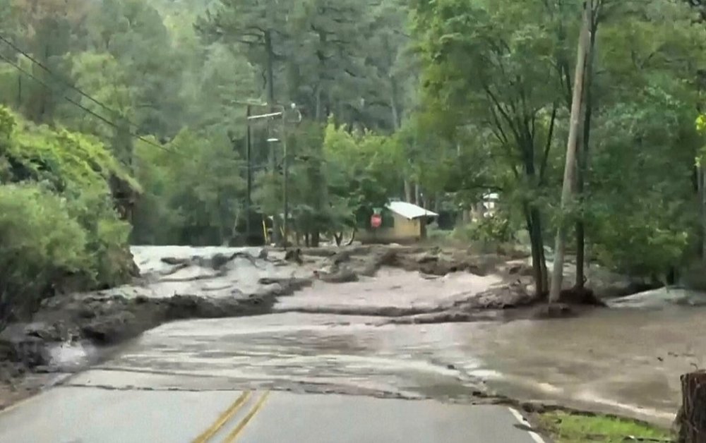 This image taken from a provided video shows flood waters flowing over a road in Ruidoso, N.M., Thursday, July 24, 2025. (Marissa Hensen via AP)