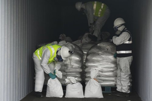 Customs workers carry bags of mercury hidden in gravel-filled bags in Lima, Peru, Wednesday, July 16, 2025. (AP Photo/Guadalupe Pardo)