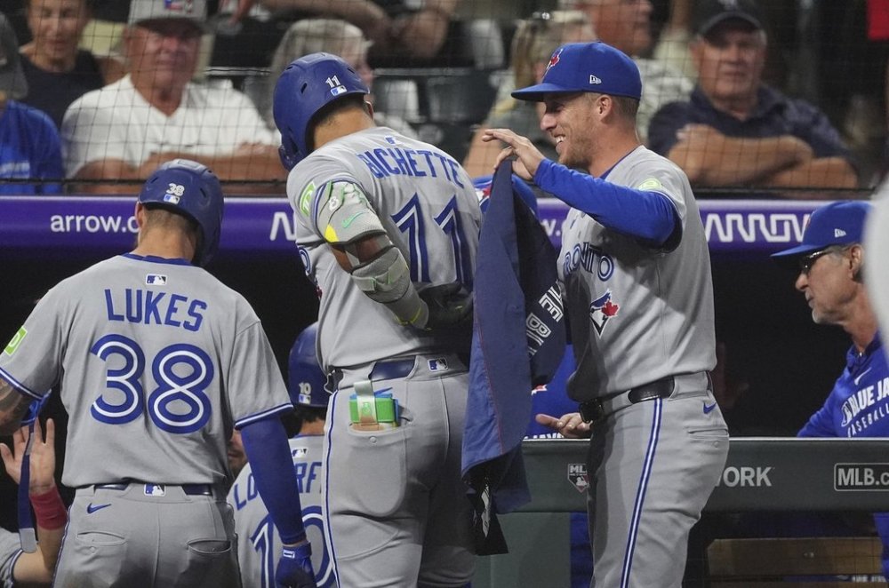 Toronto Blue Jays' Myles Straw, right, puts on a jacket for Bo Bichette as he returns to the dugout after hitting a three-run home run off Colorado Rockies relief pitcher Carson Palmquist in the seventh inning of a baseball game Monday, Aug. 4, 2025, in Denver. (AP Photo/David Zalubowski)
