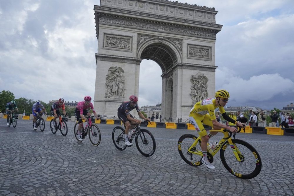 The pack with Slovenia's Tadej Pogacar, wearing the overall leader's yellow jersey, passes the Arc de Triomphe during the twenty-first stage of the Tour de France cycling race over 132.3 kilometers (82.1 miles) with start in Mantes-la-Ville and finish on the Champs-Elysees in Paris, France, Sunday, July 27, 2025. (AP Photo/Mosa'ab Elshamy)