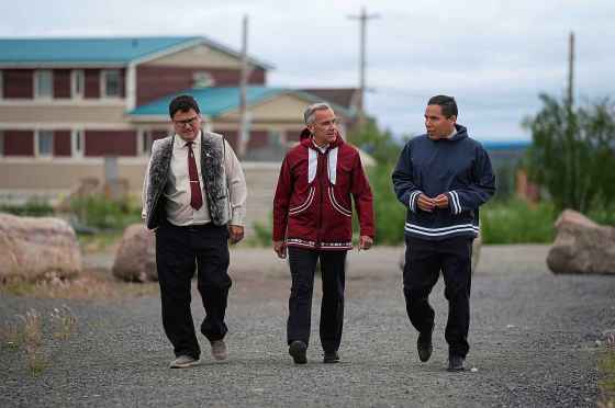 Prime Minister Mark Carney walks with Duane Smith, left, chair and CEO of the Inuvialuit Regional Corporation, and Natan Obed, right, president of the Inuit Tapiriit Kanatami, to a meeting of the Inuit-Crown Partnership Committee in Inuvik, N.W.T., on July 24. (Darryl Dyck / The Canadian Press files)