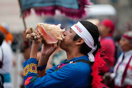 A dancer dressed in Indigenous clothing blows on a conch shell during the 700th anniversary celebration in Mexico City. (Eduardo Verdugo / The Associated Press files)