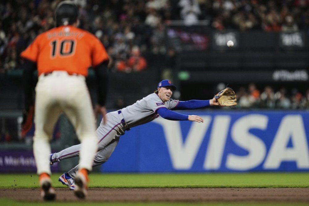San Francisco Giants' Casey Schmitt, foreground, watches as New York Mets second baseman Brett Baty is unable to catch a single hit by Patrick Bailey during the fifth inning of a baseball game Friday, July 25, 2025, in San Francisco. (AP Photo/Godofredo A. Vásquez)