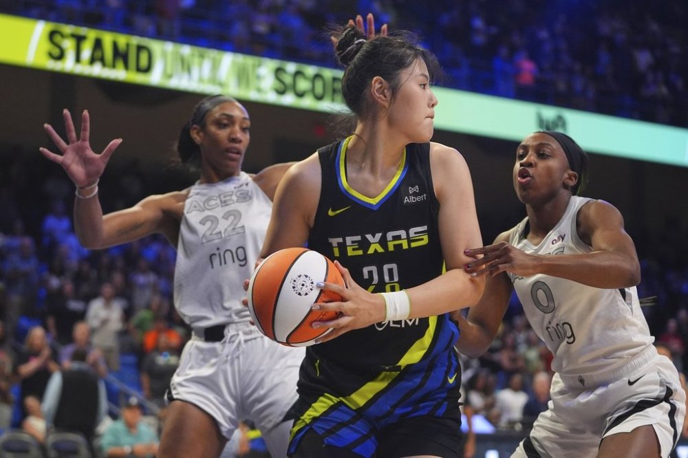 Dallas Wings center Li Yueru (28) keeps the ball from Las Vegas Aces guard Jackie Young (0) and center A'ja Wilson (22) during the first half of a WNBA basketball game in Arlington, Texas, Sunday, July 27, 2025. (AP Photo/LM Otero)