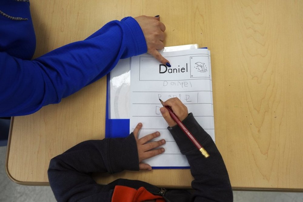 FILE - Easterseals Head Start program teaching assistant Tania Ortiz helps a student practice writing his name, Jan. 29, 2025, in Miami. (AP Photo/Rebecca Blackwell, File)