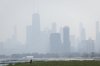 People sun tan in grass off the Lakefront Trail on the North Side as a haze of Canadian wildfire smoke blankets the Chicago area and creates poor air quality, Thursday, July 31, 2025. (Ashlee Rezin/Chicago Sun-Times via AP)