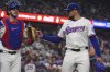 Texas Rangers starting pitcher Nathan Eovaldi, right, taps the glove of teammate catcher Jonah Heim after the third out during the fourth inning of a baseball game against the New York Yankees, Tuesday, Aug. 5, 2025, in Arlington, Texas. (AP Photo/LM Otero)