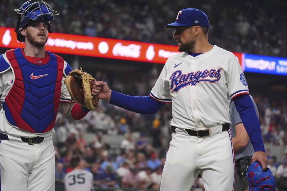 Texas Rangers starting pitcher Nathan Eovaldi, right, taps the glove of teammate catcher Jonah Heim after the third out during the fourth inning of a baseball game against the New York Yankees, Tuesday, Aug. 5, 2025, in Arlington, Texas. (AP Photo/LM Otero)