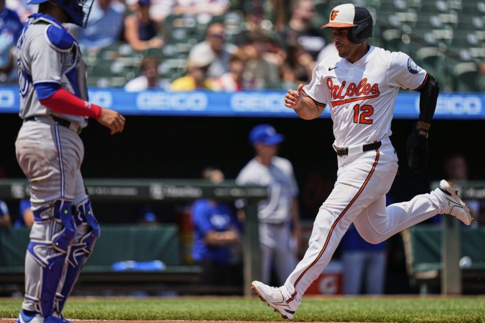 Baltimore Orioles' Ramon Laureano (12) scores past Toronto Blue Jays catcher Ali Sanchez, left, on a sacrifice fly hit by Cedric Mullins during the first inning in the first baseball game of a doubleheader, Tuesday, July 29, 2025, in Baltimore. (AP Photo/Stephanie Scarbrough)