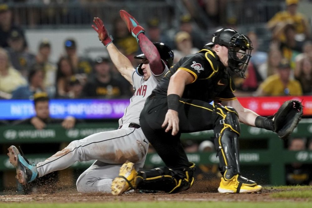 Arizona Diamondbacks' Corbin Carroll, left, scores as Pittsburgh Pirates catcher Henry Davis waits for the late throw during the eleventh inning of a baseball game, Friday, July 25, 2025, in Pittsburgh. (AP Photo/Matt Freed)