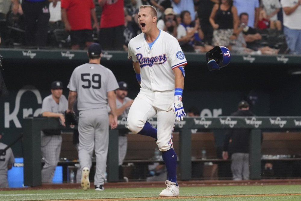 Texas Rangers' Josh Jung, right, celebrates after his home run as New York Yankees pitcher Jake Bird (59) walks to the dugout during the 10th inning of a baseball game Monday, Aug. 4, 2025, in Arlington, Texas. (AP Photo/LM Otero)