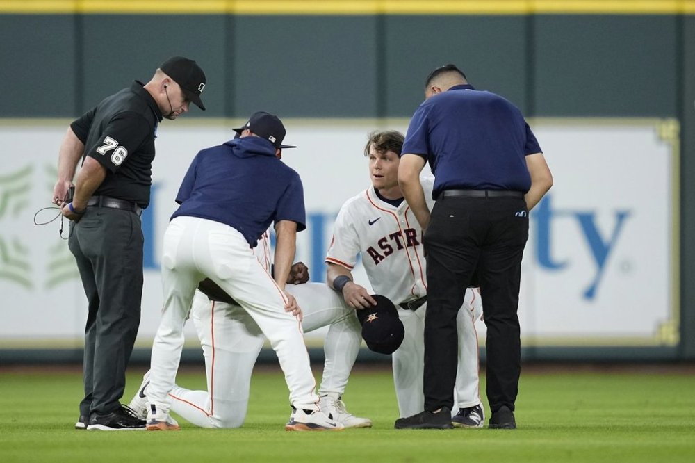 Houston Astros' Jake Meyers, second from right, kneels as a trainer talks with him while manager Joe Espada, second from left, talks with umpire Mike Muchlinski (76) before the start of a baseball game against the Cleveland Guardians Wednesday, July 9, 2025, in Houston. (AP Photo/David J. Phillip)