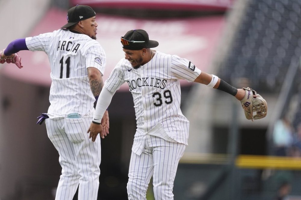 Colorado Rockies third baseman Orlando Arcia, left, and second baseman Thairo Estrada celebrate after defeating the Pittsburgh Pirates in a baseball game Saturday, Aug. 2, 2025, in Denver. (AP Photo/David Zalubowski)