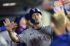 Texas Rangers' Evan Carter is greeted by teammates after hitting a home run during the eighth inning of a baseball game against the Los Angeles Angels Monday, July 28, 2025, in Anaheim, Calif. (AP Photo/William Liang)