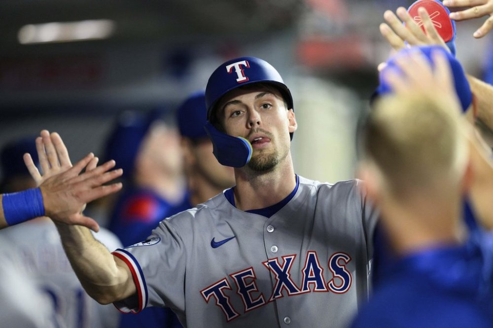 Texas Rangers' Evan Carter is greeted by teammates after hitting a home run during the eighth inning of a baseball game against the Los Angeles Angels Monday, July 28, 2025, in Anaheim, Calif. (AP Photo/William Liang)