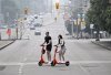 People cross Elgin Street on e-scooters in Ottawa, on Sunday, June 25, 2023. THE CANADIAN PRESS/Justin Tang