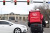 A food delivery rider waits for the traffic light to change Monday, March 30, 2020, in Lone Tree, Colo.   (AP Photo/David Zalubowski, File)