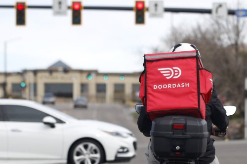 A food delivery rider waits for the traffic light to change Monday, March 30, 2020, in Lone Tree, Colo.   (AP Photo/David Zalubowski, File)