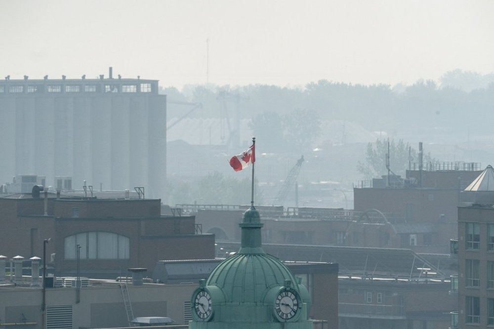 A Canadian flag flies on a flagpole amid a hazy sky, caused by smoke from wildfires burning in Canada's prairie provinces, in Toronto, Friday, June 6, 2025. THE CANADIAN PRESS/Giordano Ciampini