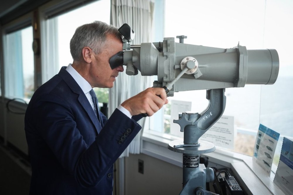 Prime Minister Mark Carney looks through high-powered ship binoculars during a visit to the Canadian Forces Maritime Experimental and Test Ranges (CFMETR) operations centre on the Winchelsea Islands near Nanoose Bay, B.C., on Monday, Aug. 4, 2025. THE CANADIAN PRESS/Darryl Dyck