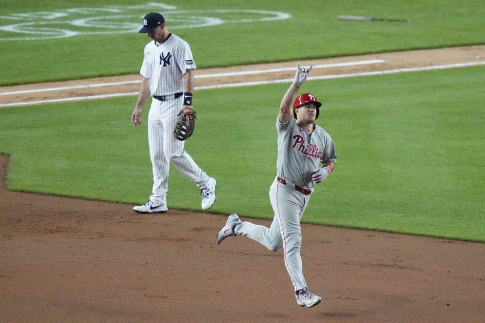 Philadelphia Phillies' J.T. Realmuto, right, runs past New York Yankees Paul Goldschmidt as he runs the bases after hitting a three-run home run during the seventh inning of a baseball game Friday, July 25, 2025, in New York. (AP Photo/Frank Franklin II)